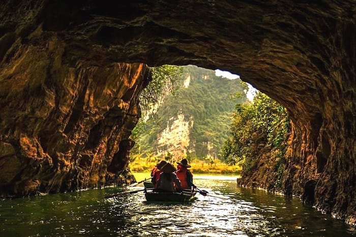 Sampan boats gliding through Trang An caves and rivers.