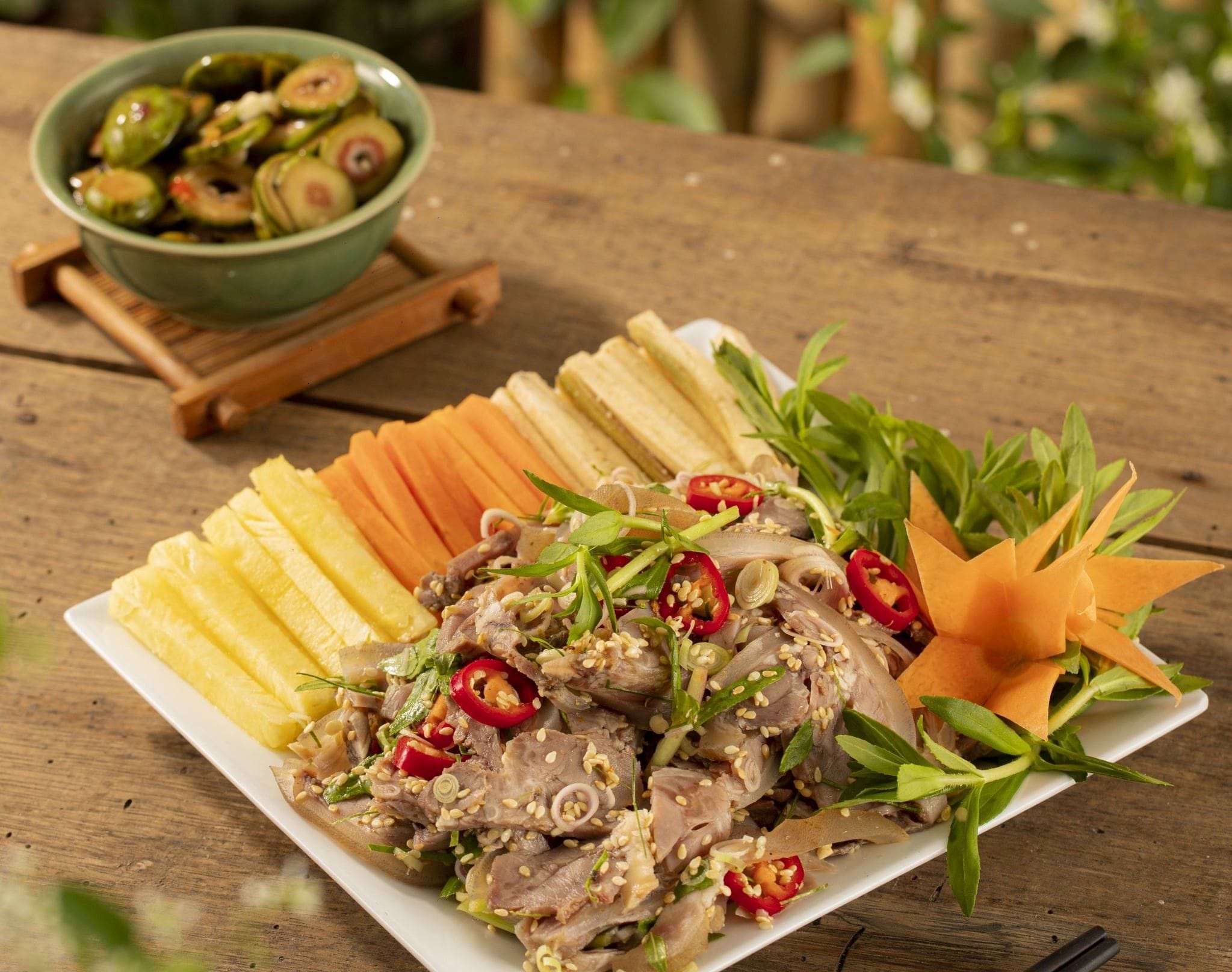 A fragrant plate of dê tái chanh (marinated mountain goat) garnished with lemongrass, chili, and sesame seeds.