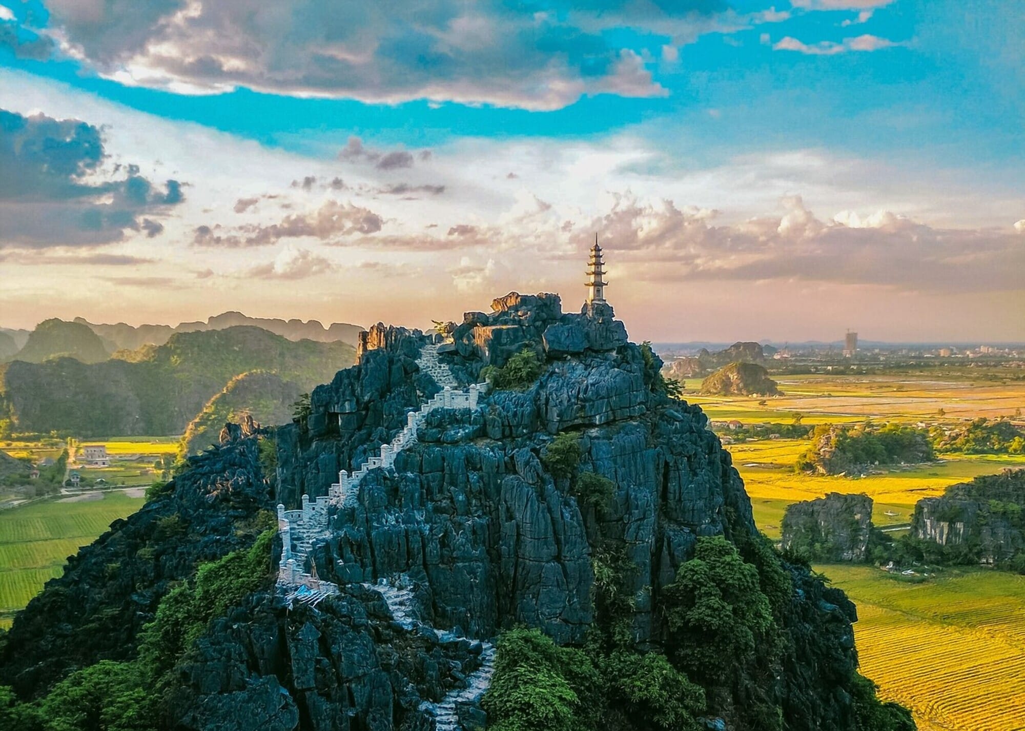 An expansive view of the limestone karsts rising dramatically from the emerald rice fields