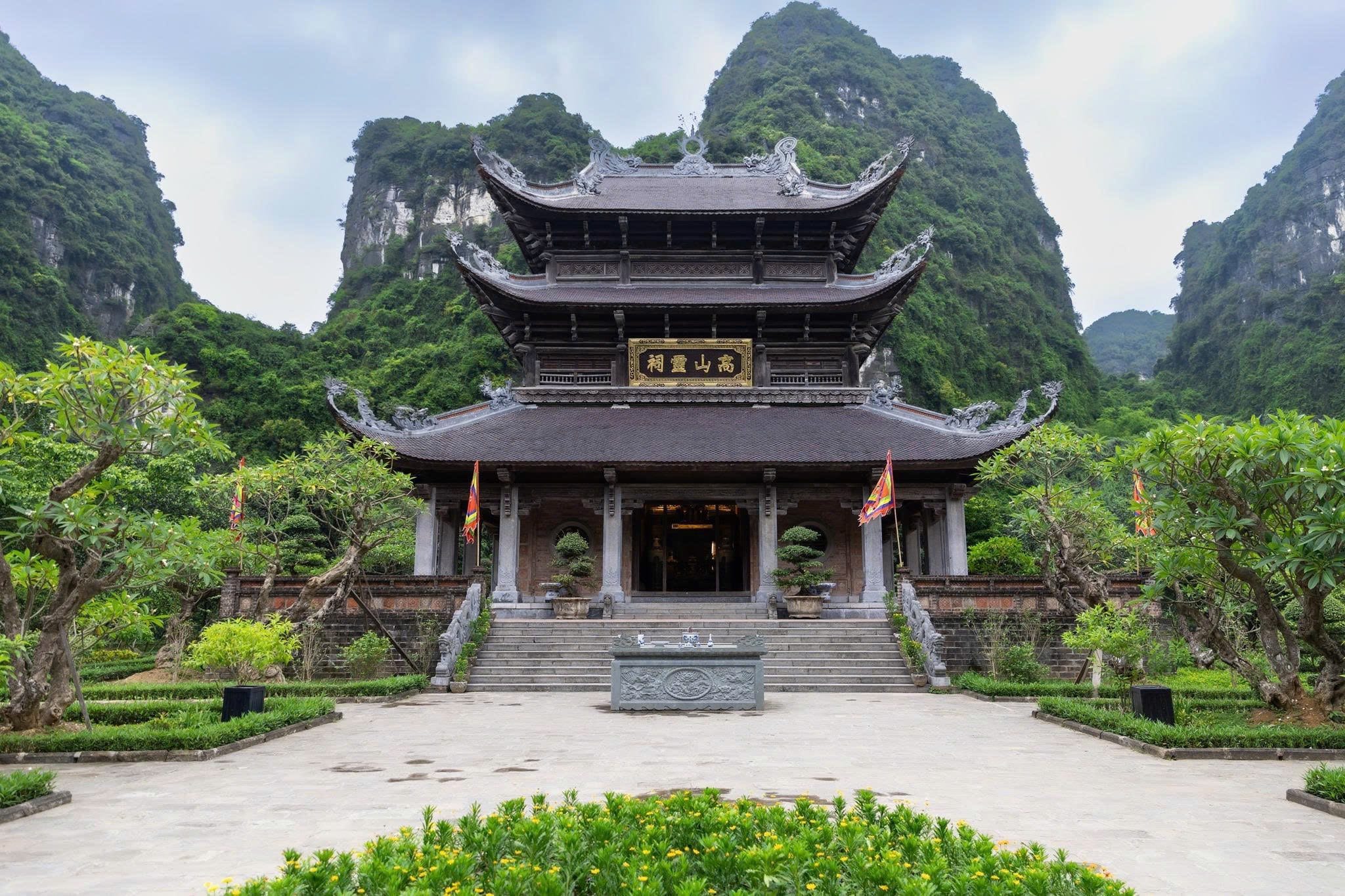 The unique three-tiered architecture (3 tầng 12 mái) of Thanh Cao Son Temple nestled harmoniously against the karst mountainside.