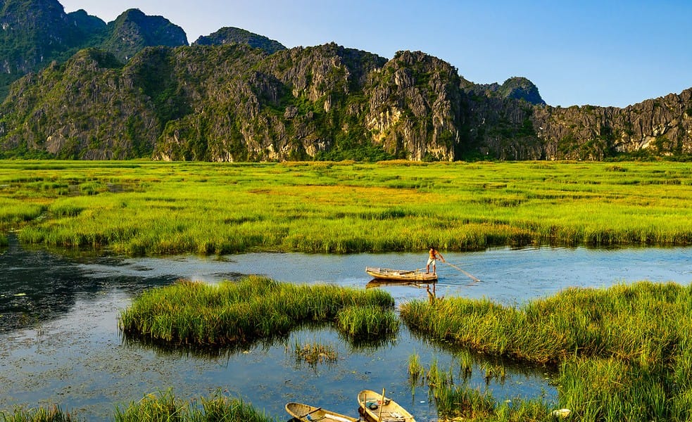 Independent eco-tourists observing rare primates on vertical limestone cliffs during a quiet sampan boat tour