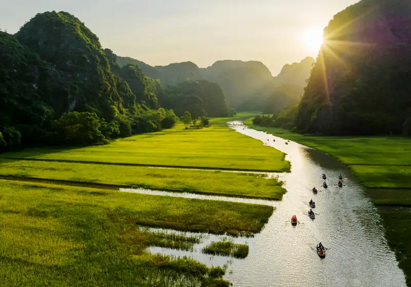 A traditional sampan gliding through the "Halong Bay on Land" during a serene tam coc boat tour.
