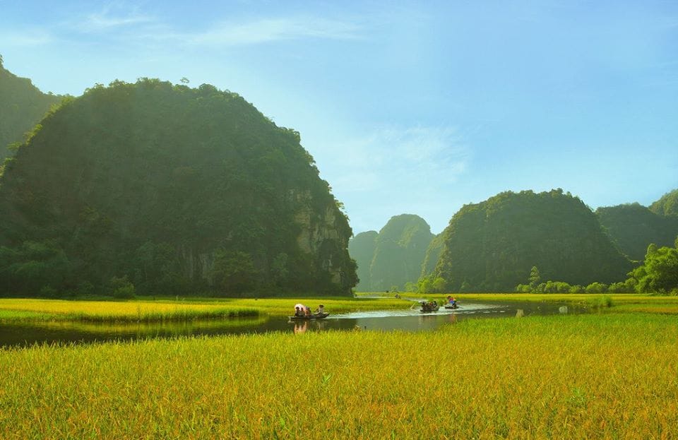 Travelers visiting a secluded water temple hidden within an enclosed mountain valley accessible only by boat.