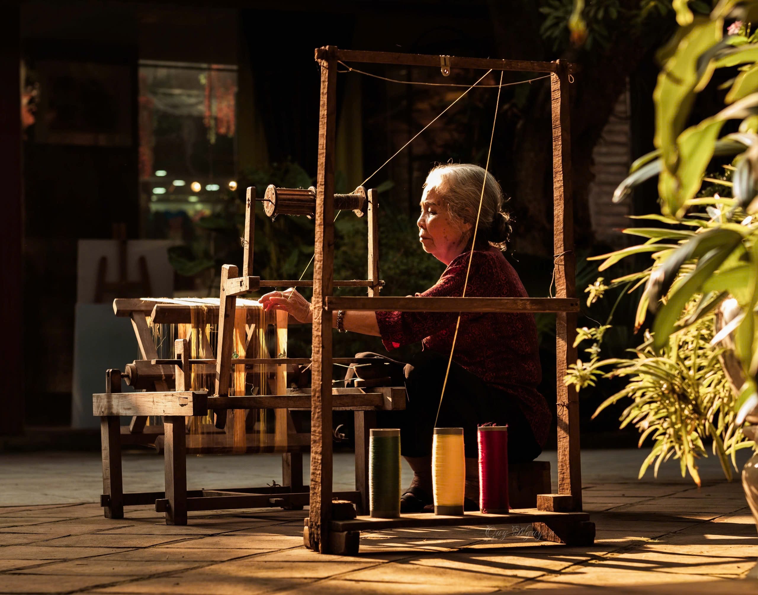 A peaceful detail shot of a local weaver working carefully in sunset courtyard